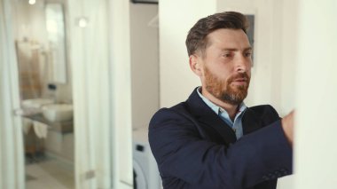 Maskeli yakışıklı işadamı aynaya bakıyor ve takım elbise giyiyor. Git ev güvenliği için çalış. Profesyonel apartman dairesi kordemik ağır çekim.