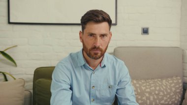 Portre çekici bir adam kameraya bakıyor ciddi işçi dizüstü bilgisayarı koltukta oturuyor internet girişimcisi bilgisayarı yavaş çekimde kapat