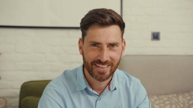 Portre çekici bir adam kameraya bakıyor ciddi işçi dizüstü bilgisayarı koltukta oturuyor internet girişimcisi bilgisayarı yavaş çekimde kapat