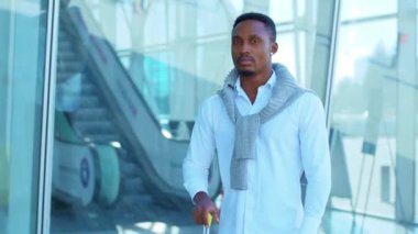 Portre, genç Afro-Amerikalı iş adamının bavulla havaalanının yakınında mutlu bir şekilde gülümseyen kameraya bakışıyla karşılaşıyor. Güven yarışı başarısı çekici. Kapatın. Yavaş çekim