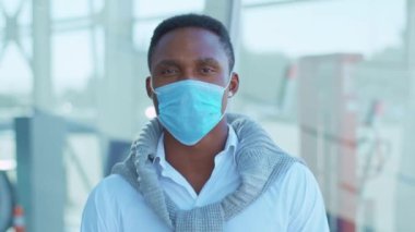 Koruyucu Yüz Maskesi takan genç Afrikalı Amerikalı adam kameraya bak. COVID-19 koronavirüs enfeksiyonu. Salgın hastalık salgını. Yavaş çekim