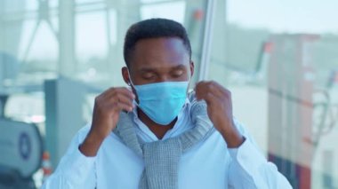 Gülümseyen Afrikalı genç Amerikalı Koruyucu Yüz Maskesi 'ni kaldırdı ve kameraya mutlu bir şekilde baktı. COVID-19 koronavirüs enfeksiyonu. Salgın hastalık salgını. Yavaş çekim