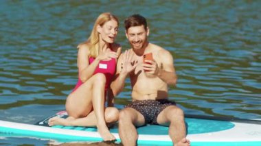 Birkaç erkek ve kadın güvertede oturup gülümsüyor sohbet ediyorlar sörf tahtası sırılsıklam su mayosu özgürlüğünü yavaş çekimde aktif hale getiriyorlar.