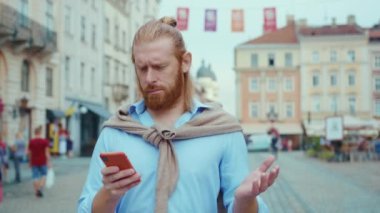Yakışıklı kızıl saçlı beyaz sakallı adam şehir merkezindeki akıllı telefon navigasyon uygulamasında kaybolmuş gibi görünüyor..