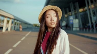 Güneşin batışında, neşeli gülüşü ve güzel saçları olan çarpıcı genç Çinli kadının portresi. Şehirdeki çekici insanlar işte. Asya kökenli. Gezgin. Moda konsepti.