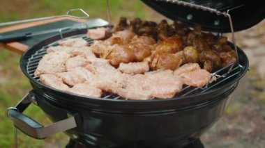 Adam bahçede mangal kömürü rendesinde ızgara yemek pişiriyor. Izgarada lezzetli somon eti ve mantar hazırlayan kişi. Piknik konsepti.