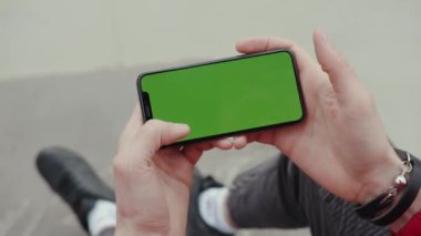 Los Angeles, Kaliforniya 15 03: 2019 EDITORIAL: Yeşil ekran arka plan bacaklı, dijital ekran akıllı telefon teknolojisi ile el ele oturan ve telefona dokunan adam