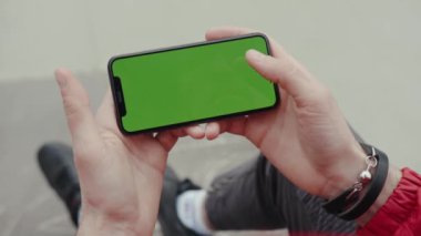 Los Angeles, Kaliforniya 15 03: 2019 Yatay yeşil ekran elli adam arka planda oturuyor ve ayaklarına dokunuyor dijital ekran akıllı telefon teknolojisi günışığı