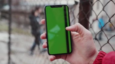 Los Angeles, California 15 03 2019 EDITORIAL: Eller dursun ve yeşil ekran dikey arka plan çiti ile telefona dokunsun dijital ekran, akıllı telefon teknolojisi günışığı