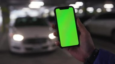 Los Angeles, Kaliforniya 15 03 03 2019 EDITORIAL: Elinde yeşil ekran ile akıllı telefonu tutan adam, beyaz otomobilin fotoğraflarını çekiyor. Bulanık görüş. Farlar. Yüz, iş, cep telefonu, cep telefonu olmadan