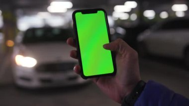 Los Angeles, California 15 03 2019 EDITORIAL: elinde yeşil ekranlı cep telefonu tutan adam, beyaz aracın fotoğraflarını çekiyor. Erkek eli cep telefonunda. Modern teknoloji kavramı.