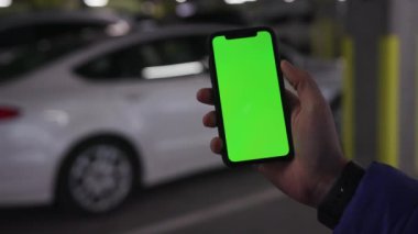 Los Angeles, California 15 03 2019 EDITORIAL: akıllı telefon tutan adam ekrana dokunuyor. İnternette erkek el sörfü, uygulamayla mesajlaşma. Arka planda beyaz otomobilin bulanık görüntüsü. Kapalı.