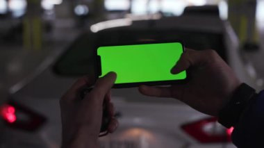 Los Angeles, California 15 03 03 2019 EDITORIAL: akıllı telefon tutan, video oyunu oynayan beyaz bir el. Yeşil ekran. Otomobilin bulanık görüntüsü. İçeride. Garajda. Yüzü olmadan, tutarak