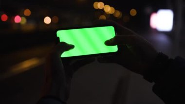 Los Angeles, California 15 03 03 2019 EDITORIAL: akıllı telefonun yeşil ekranına dokunan Kafkas parmak izleri. Arka planda sarı bulanık ışıklar. Gadget, mobil teknoloji, aygıt.