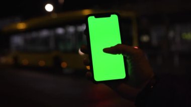 Los Angeles, California 15 03 2019 EDITORIAL: sarı tramvayın video görüntüleri. Cephede cep telefonu olan bir adamın eli. Yeşil ekran. Gadget, akıllı telefon, cihaz. İyi akşamlar, karanlık..
