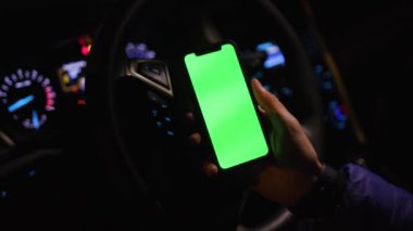 Los Angeles, Kaliforniya 15 03 03 2019 EDITORIAL: Araba tekerleğinin arkasında yeşil ekranlı akıllı telefon tutan genç beyaz adamın eli. Aracın içi. Modern teknoloji konsepti. Bulanık