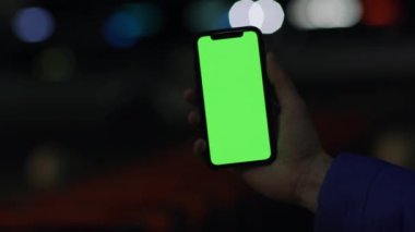 Los Angeles, California 15 03 03 2019 EDITORIAL: Gece şehir merkezinde dikey olarak krom ekran akıllı telefon tutan erkeğin yakın görüntüsü bulanıklaştı. Gadget dışarıda, gece şehrinde