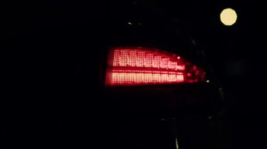 Araba farının farında kırmızı lamba ışığı yanıp sönen kırmızı araç otomobil görüntüsünü kapatıyor. Arabanın arka lambası kırmızı parlatıcı. Ulaşım ve araç konsepti, prestijli araba