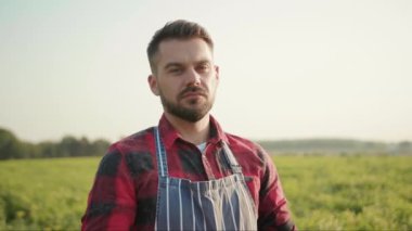 Genç çiftçi elinde bir kutu organik sebzeyle tarlada tarımsal tarım çiftliği hasadı bahçesindeki organik, açık hava, yavaş çekim kamerasına bakıyor.