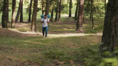 Ormanda yürürken sakallı ve sırt çantalı genç adam telefon kullanıyor. Gülümse. GPS 'e uyum sağlama, turist gezisi.