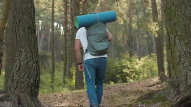 Sırt çantalı genç bir adamı günışığında ormanda yürürken vurdu. Yalnız başına orman yürüyüşü yapıyor. Genç tatilci, çekici bir sonbahar yürüyüşçüsü.