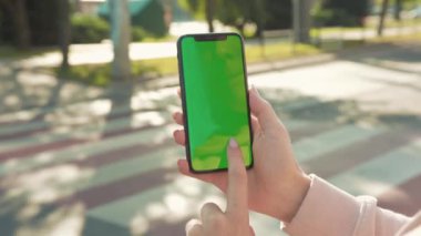 NEW YORK - 5 Nisan 2018: Arka planda dikey yeşil ekranlı telefonu tutan ve dokunan genç kadın yaya geçidi otomobili internet teknolojisi işi mesajı yavaş çekim kapatın