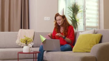 Bin yıllık olumlu genç kızıl kadın internette bayan arkadaşıyla görüntülü sohbet ederek iltifat gönderme mutluluğunu kutluyor. Doğum günü ve karantina. Tatil kavramı.