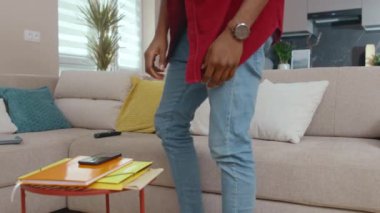 Evde genç Afrikalı bir adam telefonunu alır. Sosyal medya uygulamalarından mesajlar alır. Kanepede oturarak iletişim kurar. Modern iç mekan, gündelik yaşam tarzı.