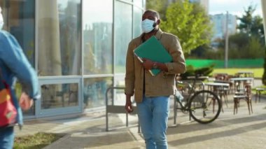 Yüz maskesi takan iki çok ırklı genç erkek öğrenci kampüsün yakınında iletişim kuran dirsek serserileriyle buluşuyor. Üniversitede. Karantina eğitimi. Kişisel güvenlik.