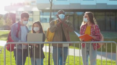 Öğrenciler arasında kamerada dur işareti gösteren Afro-Amerikalı bir adam yüz maskesi takıyor. Uzaktan eğitim. Salgın, karantina kısıtlaması.