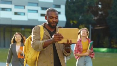 Dijital tablet kullanarak bitirdiği akademik projelerini çok ırklı arkadaşlarına gösteren mutlu Afro-Amerikanlar. Akıllı nesil. Başarı, duygular.