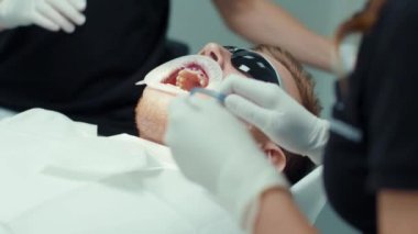 Genç yüz ve el dişçisi diş teli takıyor. Ortodontiste resepsiyon. Cilalıyorum. Ağız cerrahisi kliniği dişleri. Yavaş çekim