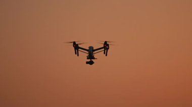 Turuncu kırmızı günbatımı arka planında uçan bir helikopterin güzel görüntüsü. Modern cihazlar. Teknoloji. Seyahat.