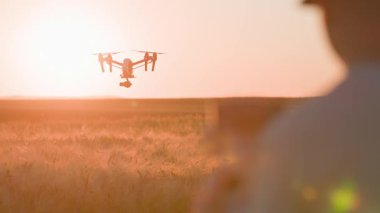 Dijital kamerayla fırlatılan kuadkopter görüntüsü. İnsansız hava aracını kontrol eden adamın arka çekimi. Kırsal kesimde. Köy. Manzara. Tarımda akıllı modern teknolojiler. Açık hava.