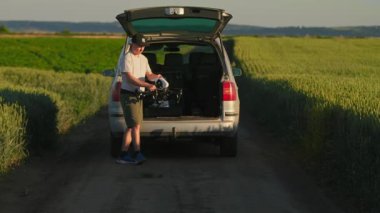 Quadcopter 'ı elinde tutan ve kırsala insansız hava aracı gönderen genç beyaz bir adam. Doğa, teknoloji, yaz, tatil. Profesyonel fotoğrafçı. Hobi, eğlence, modern