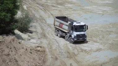 Büyük taş ocağında kamyon sürerken, inşaat malzemeleri taşırken görüntüler. Hareket halindeki aracın drone görüntüsü. Gündüz vakti. Üretim, ulaşım, endüstri. Açık havada.