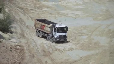 Taş ocağında kamyon çarpması, ezilmiş taşları taşıma, madencilik ürünlerini taşıma. Aracın üst görüntüsü. Panorama. Maden üretimi. Makineler. Açık hava.