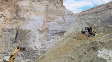 Kazı makinesi açık çukurda çalışıyor. Aracın görüntüsü. Kum çıkarma, inşaat malzemeleri. Drone kum ocağının üzerinden ateş ediyor. Doğa, çevre. Gündüz vakti. Yukarıdan görüntüle