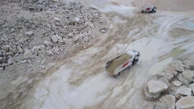 Büyük damperli kamyonların kum ocağında vurulması. Çukur. Araçların üst görüntüsü. Taşlarla dolu endüstriyel bir yer. Gündüz vakti. Madencilik endüstrisi. İnşa malzemeleri