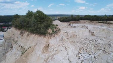 Kum ocağında çalışan kazıcının görüntüsü. Gündüz, yaz. Araç hareket halinde. Açık çukur, madencilik endüstrisi. Taş ocağı. İHA saldırısı. Açık havada. Taşıma, etkinlik