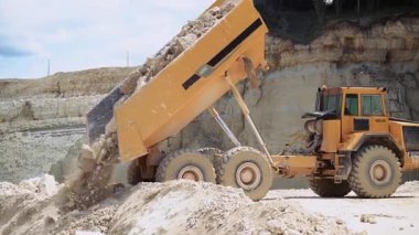 Çöp kamyonunun kum ocağına taş boşaltma görüntüsü. Açık havada çalışan bir makine. İnşaat malzemeleri üretimi ve kum çıkarımı