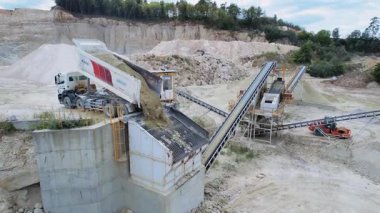 Ağır makineler ve inşaat malzemeleri. Taş ocağındaki endüstriyel taşıma sistemine taşları boşaltan bir çöp kamyonu. Kum çıkarma konsepti. İnşaat malzemeleri. Drone görüntüsü, ulaşım. Madencilik teknolojisi