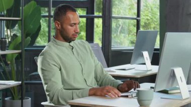 Çok çalışan, naneli tişörtlü Afro-Amerikan bir adamın bilgisayarın başında oturup klavyeyle yazı yazması, göz gezdirmesi. Baş ağrısı çeken yorgun adamın portresi. Ofis, işkolik. İçeride, gündüz vakti.