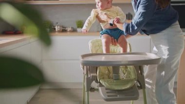 Genç anne, çok fonksiyonlu bebek koltuğunda çok fonksiyonlu küçük kızına bakıyor. Taşınabilir yemek koltuğu. Güvenlik. İçeride. Daire, ev.