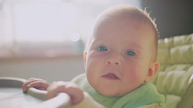 Kahverengi gözlü, kameraya bakan küçük bir çocuğun portresi. Bebek koltuğunda oturan komik çocuk. Gündüz vakti. Ebeveynlik. Dikkat et, aşkım. Yemek, yemek, beslenme.