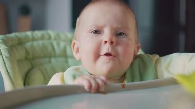 Küçük şirin bir çocuğun portresi. Burnuna püre sürülmüş. Öğle yemeği sırasında yemek için bekliyor. Mutfağa. Mutlu bir çocukluk. Modern mutfağın içi bulanık görünüyor. Kapalı