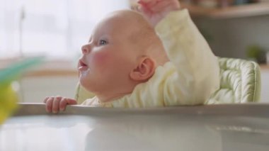 Yüksek sandalyeyi besleyen sevimli bebek. Yemeğe hazırlanıyorum. Modern daireler. Akşam yemeği. Mutfağa. Kapatın. Yavaş çekim