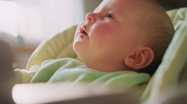 Hapşıran çocuğun yüzünü kapat ve beslenme sandalyesinde oturan taraflara bak. Anne çocuğu beslemeye çalışıyor. Güneş ışığı. Gülümsüyor. Çok komik. Yavaş çekim