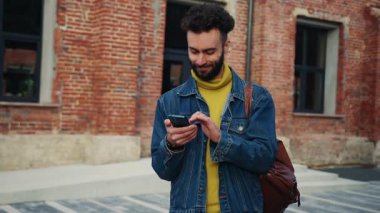 Dost canlısı görünümlü bir öğrencinin elinde akıllı telefonlar, mesajlar ve mesajlar tutarken çekilmiş görüntüleri. Sokaklarda alet kullanan genç bir hippi. Açık havada. Kot ceket giyen sakallı adam. Şehre. İletişim