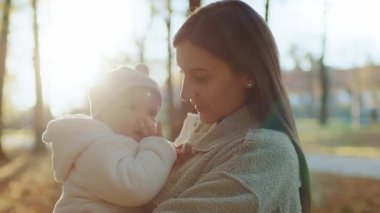 Güzel, genç, beyaz bir anne kucağında komik bebek şapkası takan küçük bir kız çocuğu. Gülümseyen bebek ve annesi parkta. Sonbahar. İyi günler. Aile kavramı. Dikkat et aşkım.